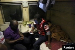 Gilbert Mthinzima Ndlovu (R), a veteran of Zimbabwe's 1970s independence war and a security guard at the National Railways of Zimbabwe (NRZ) for 35 years, chats to his colleague in a carriage during an overnight train journey from Harare to Bulawayo, Zimbabwe, Aug. 5, 2018.