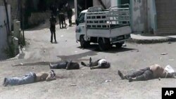 This citizen journalist image provided by The Syrian Revolution against Bashar Assad, which has been authenticated based on its contents and other AP reporting, shows Syrian army soldiers standing in front of dead bodies at Bayda village.