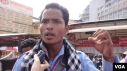 Sambath Vorn stands before a handful of protesters at the Sorya Transportation company in Phnom Penh, shouting through a megaphone.