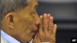 In this photo released by the Extraordinary Chambers in the Courts of Cambodia, Kaing Guek Eav, also known as Duch, who ran the notorious Toul Sleng detention center, greets court officers during his appeal at the U.N.-backed war crimes tribunal in Phnom 