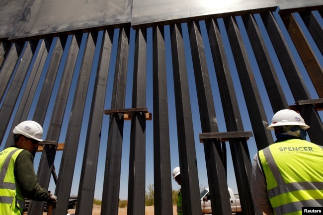 FILE - Construction workers check a new section of bollard wall in Santa Teresa, N.M., as seen from the Mexican side of the border in San Jeronimo, on the outskirts of Ciudad Juarez, Mexico,