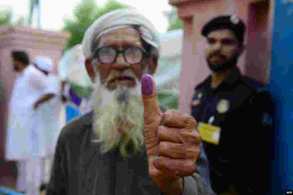 An elderly Pakistani man shows his inked thump after casting his vote outside a polling station during general election in Lahore.