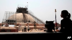 A Nepalese woman looks at the reconstruction work at the Boudhanath Stupa which was damaged in last year's earthquake in Kathmandu, Nepal, Monday, April 25, 2016.(AP Photo/Niranjan Shrestha)