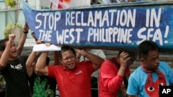 FILE - Protesters carry a boat painted with slogans during a rally outside the Chinese Consulate in Makati city, east of Manila, Philippines, to protest China's reclamations of disputed islands off South China Sea, July 3, 2015. 