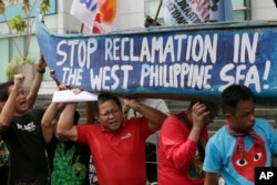 Protesters carry a boat painted with slogans during a rally outside the Chinese Consulate in Makati city, east of Manila, Philippines, to protest China's reclamations of disputed islands off South China Sea, July 3, 2015.