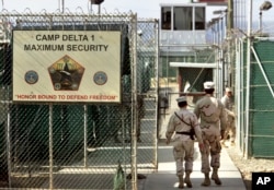 FILE - U.S. military guards enter the Camp Delta military-run prison, at the Guantanamo Bay U.S. Naval Base, Cuba, June 27, 2006.