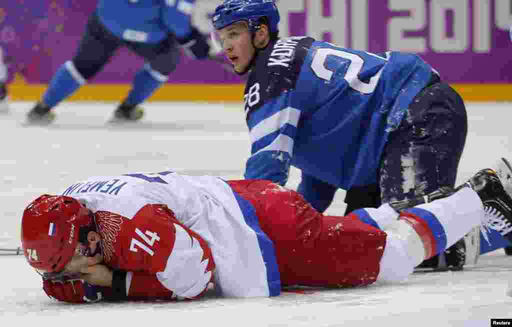 Alexei Yemelin dari Rusia memegang wajahnya setelah terkena pukulan Lauri Korpikoski dari Finlandia (kanan) pada babak kedua perempat final hoki es, Sochi, 19 Februari 2014.