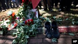 Sepasang sepatu milik korban terlihat berada di dekat rangkaian bunga, yang diletakkan oleh para pelayat di lokasi ledakan di kota Suruc, Turki, dekat perbatasan Suriah (21/7). 