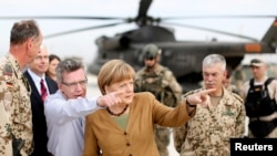 Germany's Chancellor Angela Merkel (C) points with German Minister of Defense Thomas de Maiziere as she makes a surprise visit to Bundeswehr base in Kunduz, Afghanistan, May 10, 2013.