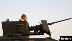 A member of the Kurdish Peshmerga forces stands in a military vehicle in Jalawla, Diyala province, Iraq, July 3, 2014.