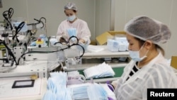 Members of staff collect surgical masks from a production line in a factory in Taoyuan, Taiwan April 6, 2020. (REUTERS/Ann Wang)