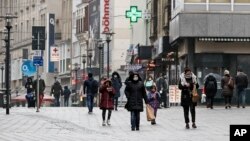 Only a few people, wearing mandatory medical masks, walk on the main shopping street in Essen, Germany, during the lockdown due to the COVID-19 pandemic on Tuesday, Feb. 2, 2021. (AP Photo/Martin Meissner)