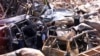 Polisi forensik berjalan melewati mobil yang hancur di dekat lokasi ledakan bom 12 Oktober 2002 di Kuta Bali, 18 Oktober 2002. (Foto: Reuters)