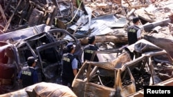 Polisi forensik berjalan melewati mobil yang hancur di dekat lokasi ledakan bom 12 Oktober 2002 di Kuta Bali, 18 Oktober 2002. (Foto: Reuters)