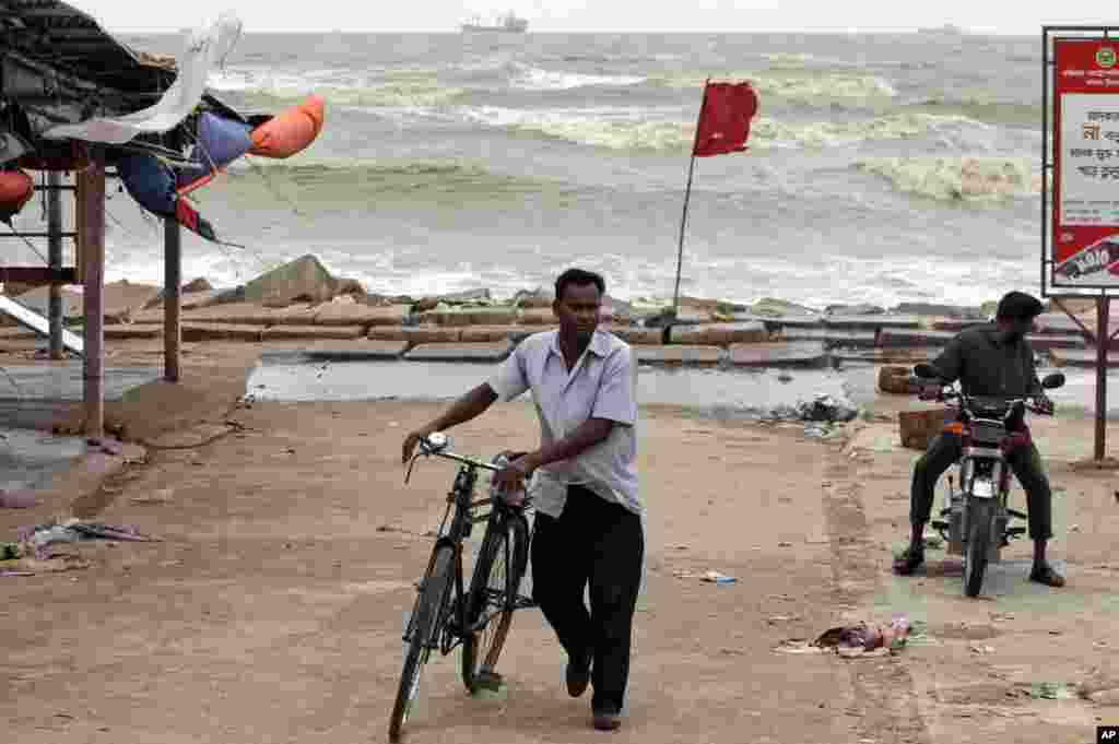 Bangladeshi commuters move past a red flag warning people of the coming tropical cyclone Mahasen by the coast of the Bay of Bengal in Chittagong, Bangladesh, May 16, 2013.