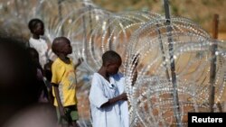 Internally displaced boys stand next to barbed wire inside a United Nations Missions in Sudan (UNMIS) compound in Juba December 19, 2013. 