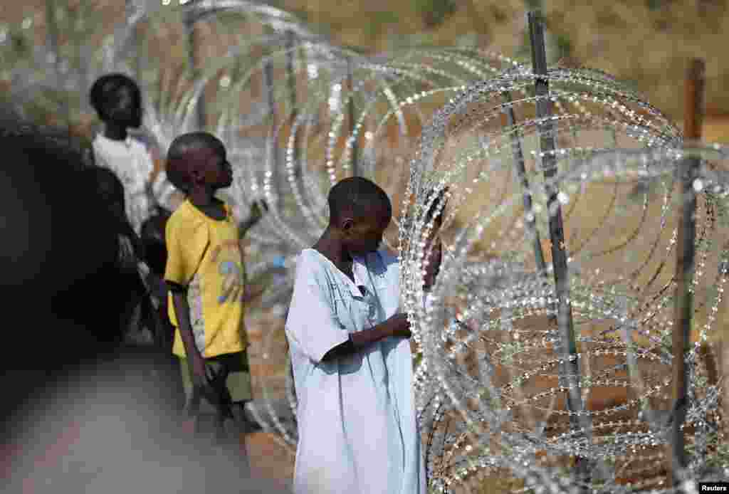 Internally displaced boys stand next to barbed wire inside a United Nations Mission in a South Sudan compound, Juba, South Sudan, Dec. 19, 2013. 