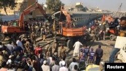 Rescuers workers use heavy machinery on the car of a train which crashed outside Karachi, Pakistan, Nov. 3, 2016.