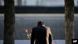 FILE - A man stands at the edge of a waterfall pool at ground zero during a ceremony on the 16th anniversary of the 9/11 attacks in New York, Sept. 11, 2017. 