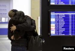 A couple embraces next to a flight information board at Pulkovo airport in St. Petersburg, Oct. 31, 2015.