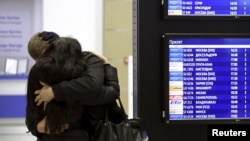 A couple embraces next to a flight information board at Pulkovo airport in St. Petersburg, Oct. 31, 2015. 