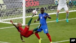 Bacary Sagna de la France, à droite, tente de contrer un «ciseau » de Ricardo Quaresma du Portugal lors de la finale de l’Euro 2016 entre l’équipe nationale portugaise et française au Stade de France à Saint-Denis, Paris, 10 Juillet 2016. 