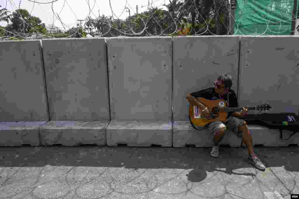 An anti-government protester plays a guitar near a barricade outside the compound of the Thai Royal Police Club in Bangkok, Jan. 29, 2014.&nbsp;