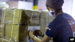 Dr. Abhu Kaur of Khalsa Aid USA, a global humanitarian organization, labels a pallet of electrical transformers, which will be shipped to New Delhi with oxygen concentrators this week on New York’s Long Island, Friday, May 7, 2021. (AP Photo/Jessie Wardar