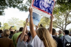 FILE - A supporter of Democratic presidential candidate Hillary Clinton attempts to block a Republican presidential candidate Donald Trump supporter from waving a sign as Clinton greets supporters in Pompano Beach, Florida, Oct. 30, 2016.