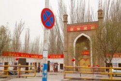 FILE - A mosque with the banner "Love the Party, Love the Country" is seen near Shule county in northwestern China's Xinjiang Uyghur Autonomous Region, March 20, 2021.