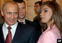 FILE - President Vladimir Putin, left, speaks with gymnast Alina Kabaeva at a Kremlin banquet in Moscow, Russia, Nov. 4, 2004.