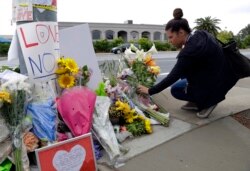 FILE - A woman leaves flowers on a growing memorial across the street from the Chabad of Poway synagogue in Poway, California, April 29, 2019.