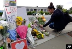 FILE - A woman leaves flowers on a growing memorial across the street from the Chabad of Poway synagogue in Poway, California, April 29, 2019.