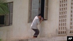 A Cambodian student tries to throw the form of hand-delivered crib notes to help his friends while they are examining inside the Phnom Penh's school, file photo. 