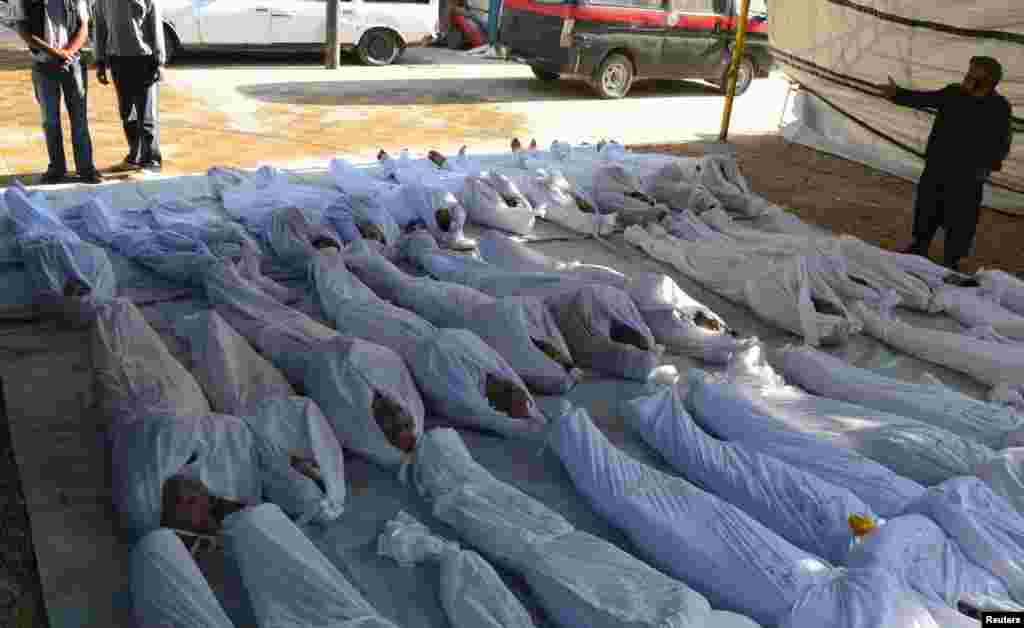 Syrian activists inspect the bodies of people they say were killed by toxic gas near Damascus, August 21, 2013. 