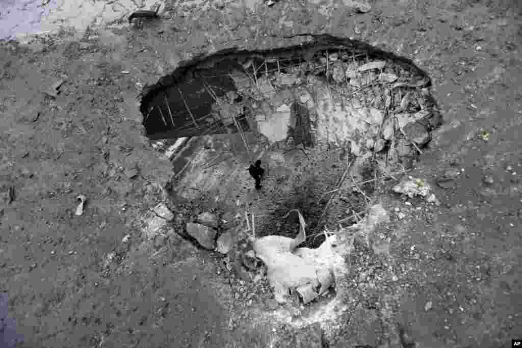 A man is seen through a crater created by a rocket from underneath a bridge in Donetsk, Feb. 9, 2015.