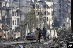 This photo released by the Syrian official news agency SANA shows Syrian troops and pro-government gunmen in the Ansari neighborhood, east Aleppo, Syria, Dec 23, 2016.