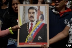 Supporters of Venezuelan President Nicolas Maduro hold a portrait of him in a ceremony to swear him in symbolically in front of the National Assembly building during a rally around the city in Caracas, Jan. 7, 2019.