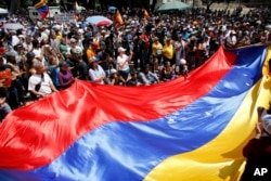 FILE - Anti-government demonstrators wave a Venezuelan flag during a protest against Venezuela's President Nicolas Maduro in Caracas, Aug. 12, 2017.
