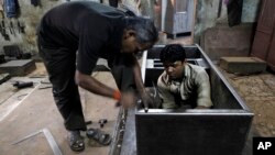 An Indian worker hammers on a steel cupboard at a metal wardrobe factory in Mumbai, India, Oct. 12, 2012.