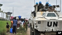 Inhabitants of the Abobo district in Abidjan flee the area past a United Nations armored vehicle following fresh clashes between forces loyal to rival claimants for the presidency on February 27, 2011