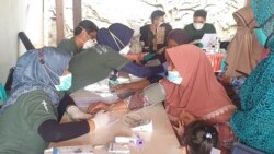 Beberapa lansia diperiksa oleh dokter dan perawat dari Kalingga di posko kesehatan (foto Petrus Riski-VOA).