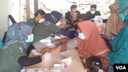 Beberapa lansia diperiksa oleh dokter dan perawat dari Kalingga di posko kesehatan (foto Petrus Riski-VOA).