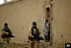 FILE - British soldiers from the NATO-led International Security Assistance Force patrol as Afghan kids look on in the outskirts of Kabul, Afghanistan, Jan. 27, 2006.