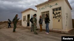 Members of the Kurdish People's Protection Units chat in front of a base captured from an Islamist Syrian rebel group in Al-Rmelan, Qamshli province. Kurdish militias are solidifying a geographic and political presence in the war-torn country.