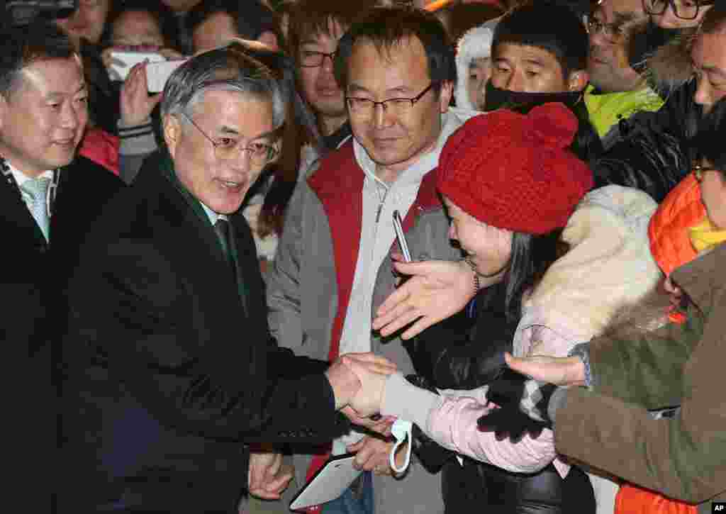 South Korean opposition Democratic United Party's presidential candidate Moon Jae-in, second from left, shakes hands with supporters after he cast his ballot in the presidential election in Seoul, Dec. 19, 2012.