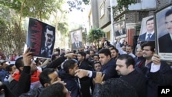 Carrying pictures of Syrian President Bashar Assad, a group of Syrians, some supporters of Assad, right, and some opposed to his regime, left, stage a protest outside the Syrian embassy in Cairo, Egypt, March 15, 2011