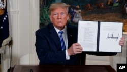 President Donald Trump shows a signed Presidential Memorandum after delivering a statement on the Iran nuclear deal from the Diplomatic Reception Room of the White House, Tuesday, May 8, 2018, in Washington.