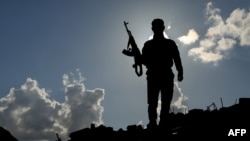 A fighter of the U.S.-backed Syrian Democratic Forces stands guard in the front-line Syrian village of Baghuz, Feb. 18, 2018. SDF forces have been fighting against the last shred of the Islamic State group's caliphate in eastern Syria.