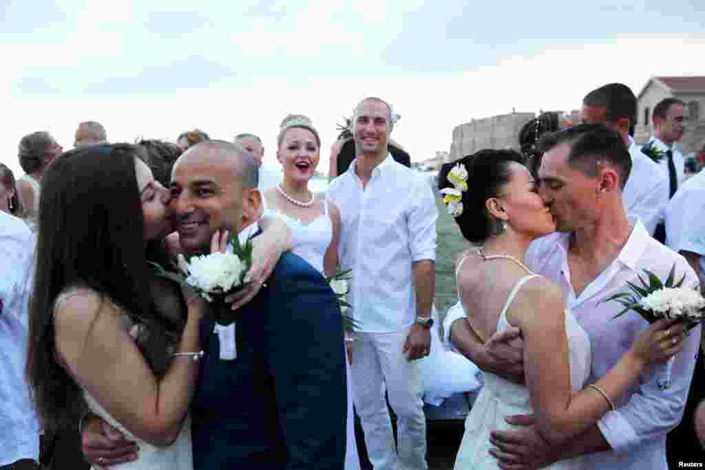 Couples kiss during a mass wedding in the coastal city of Larnaca, Cyprus. According to local media around 70 couples from Russia and Israel tied the knot on the Mediterranean island.